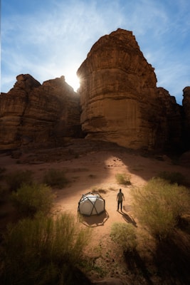 a man standing next to a tent in the desert