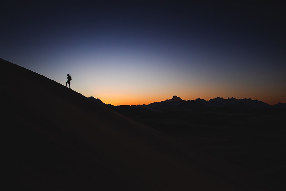 uma pessoa em pé no topo de uma montanha ao pôr do sol