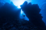 Underwater shot of a diver swimming through a stunning cavern illuminated by natural light.