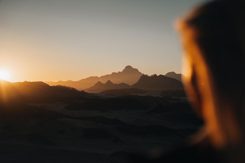 the sun is setting over a mountain range