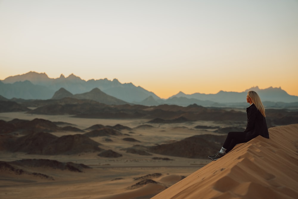 Una donna seduta sulla cima di una duna di sabbia