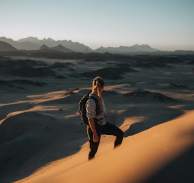 a woman standing on top of a sand dune