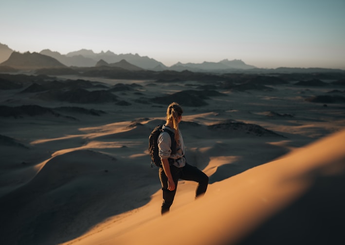 a woman standing on top of a sand dune