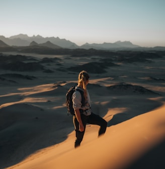 a woman standing on top of a sand dune