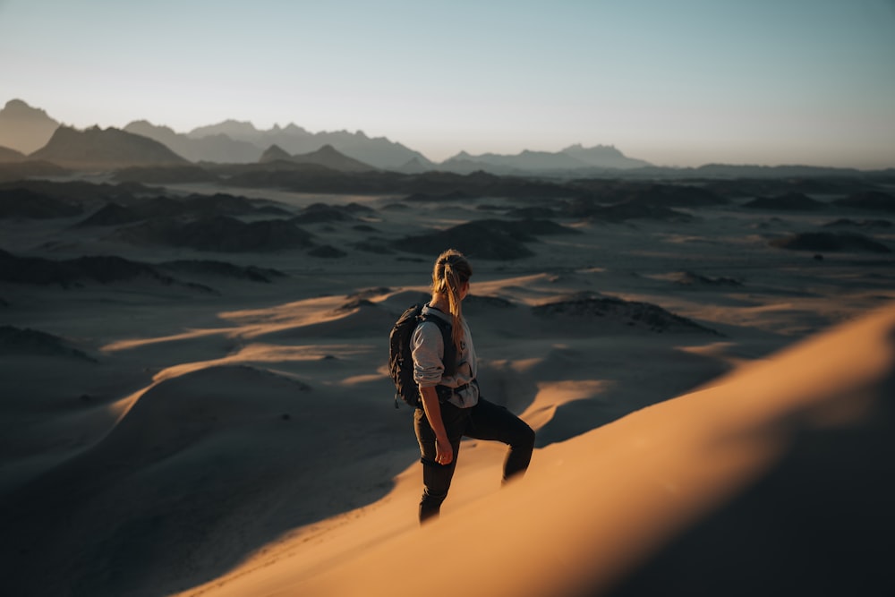 Une femme debout au sommet d’une dune de sable