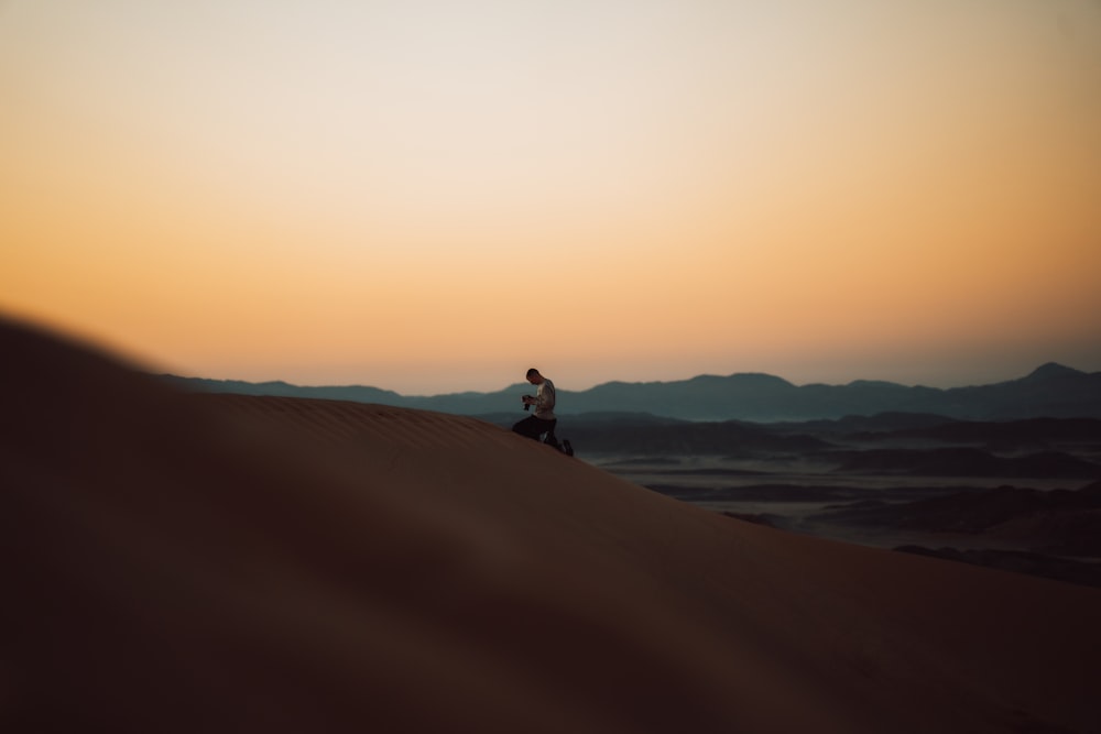 Una persona sentada en la cima de una duna de arena
