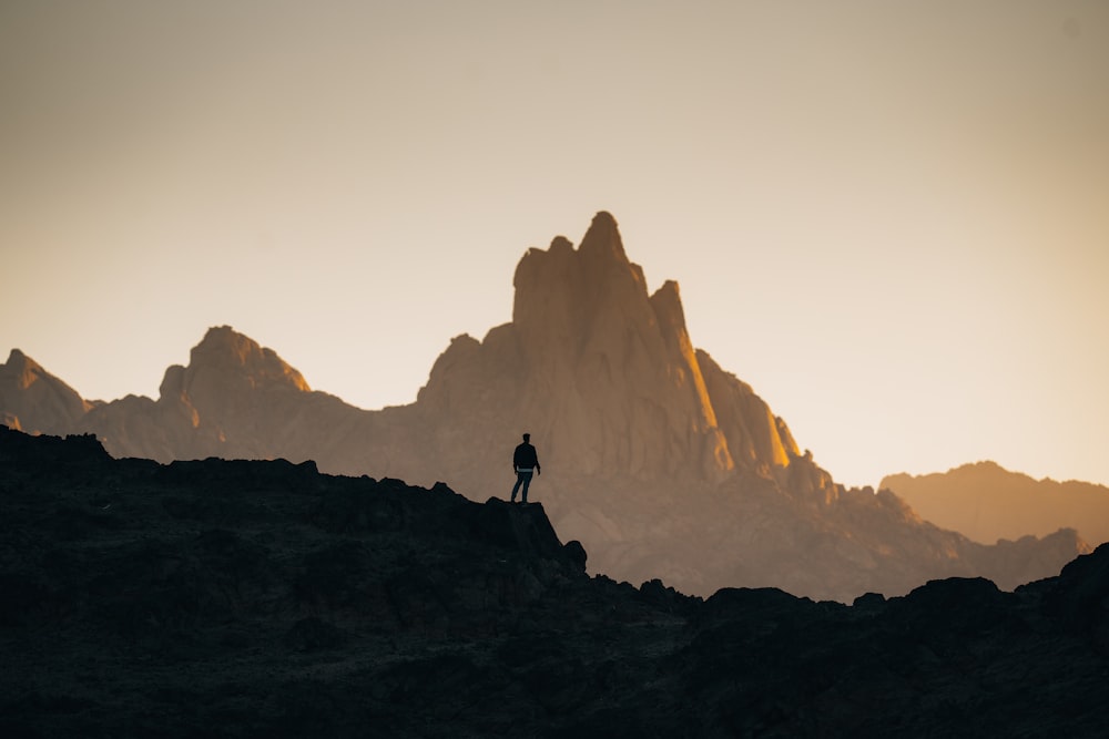 una persona in piedi sulla cima di una collina rocciosa