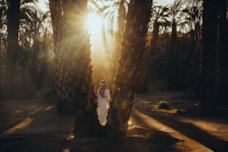 a woman is standing between two palm trees