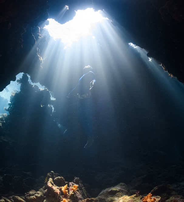 a sunbeam shines through a cave in the ocean