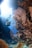 A diver equipped with snorkeling gear swims near vibrant coral reefs under clear blue water. Sunlight beams from above, illuminating the diverse marine life. The scene is serene and mesmerizing, showcasing a beautiful underwater landscape full of colorful corals and various small fish.