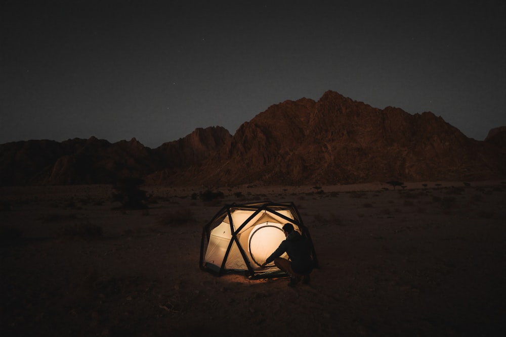 a person sitting inside of a tent in the desert