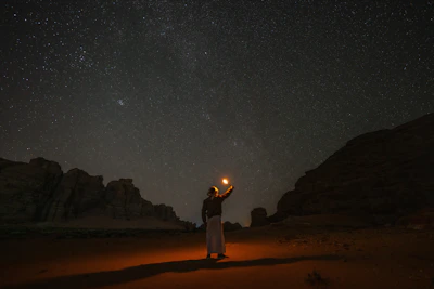 A mysterious shadowy figure performing a ritual under the moonlight in a desert landscape.