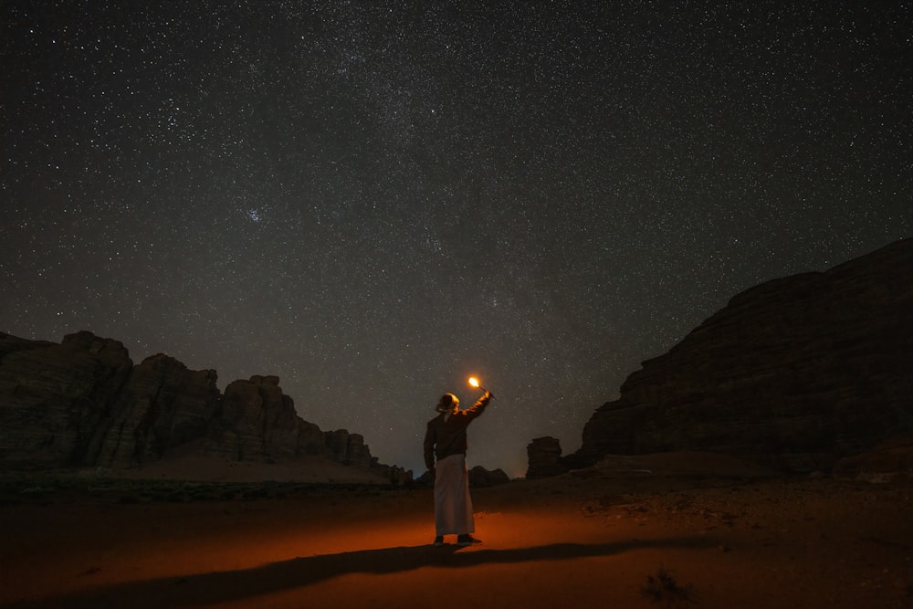 Una persona parada en el desierto sosteniendo una linterna