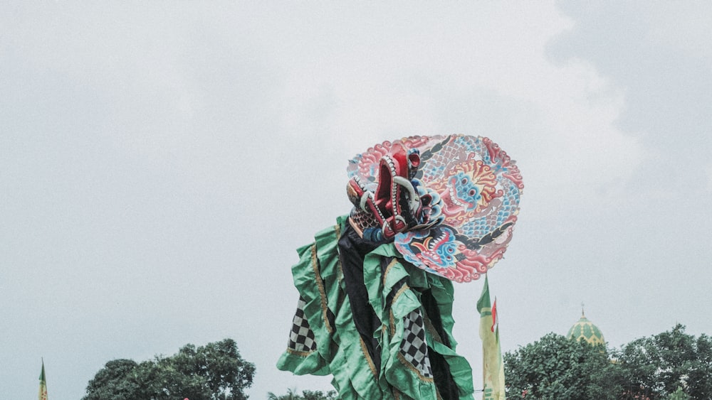 uma mulher em um vestido verde segurando um guarda-chuva