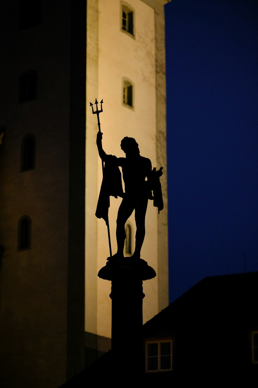 a statue of a man holding a sword in front of a tall building