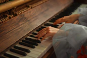 Close-up of hands playing piano keys with soft natural light.