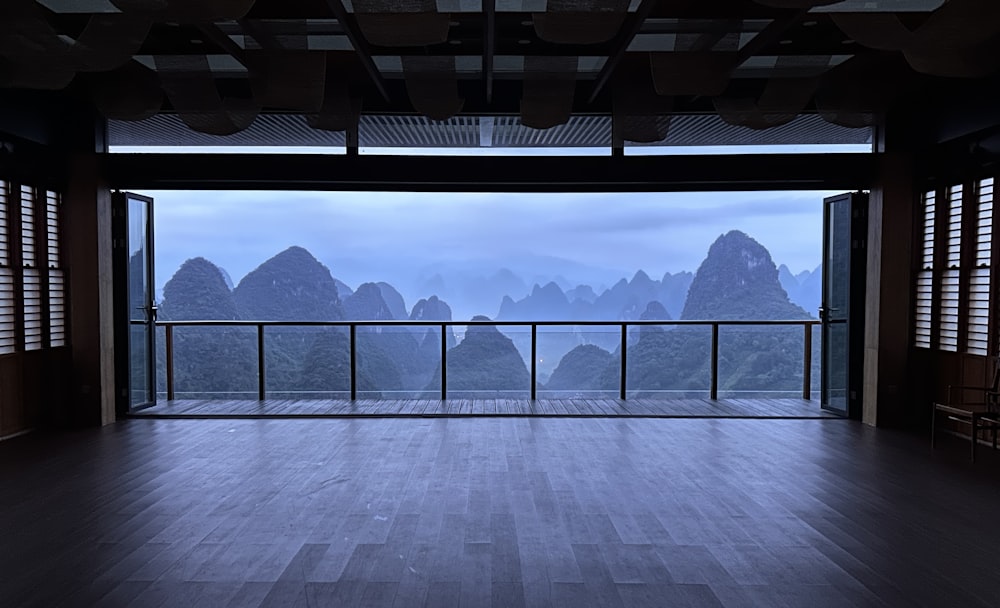 an empty room with a balcony overlooking mountains
