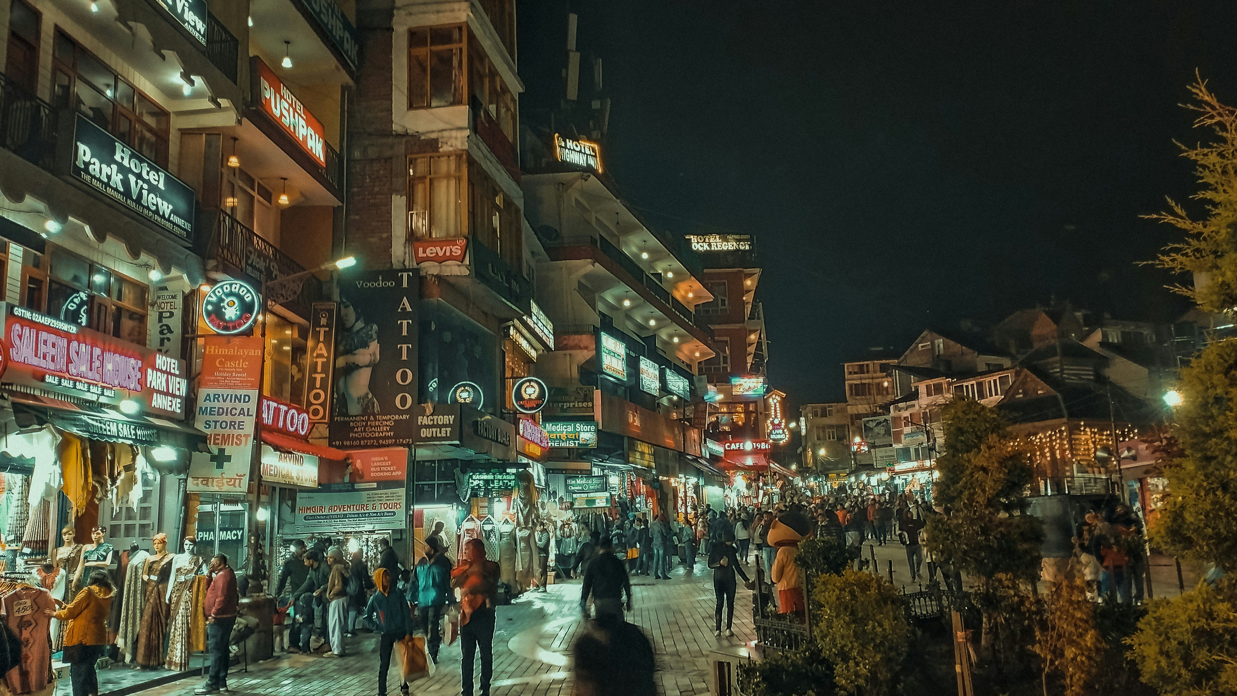 a group of people walking down a street next to tall buildings