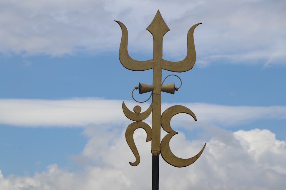 a weather vane on a pole with a sky in the background