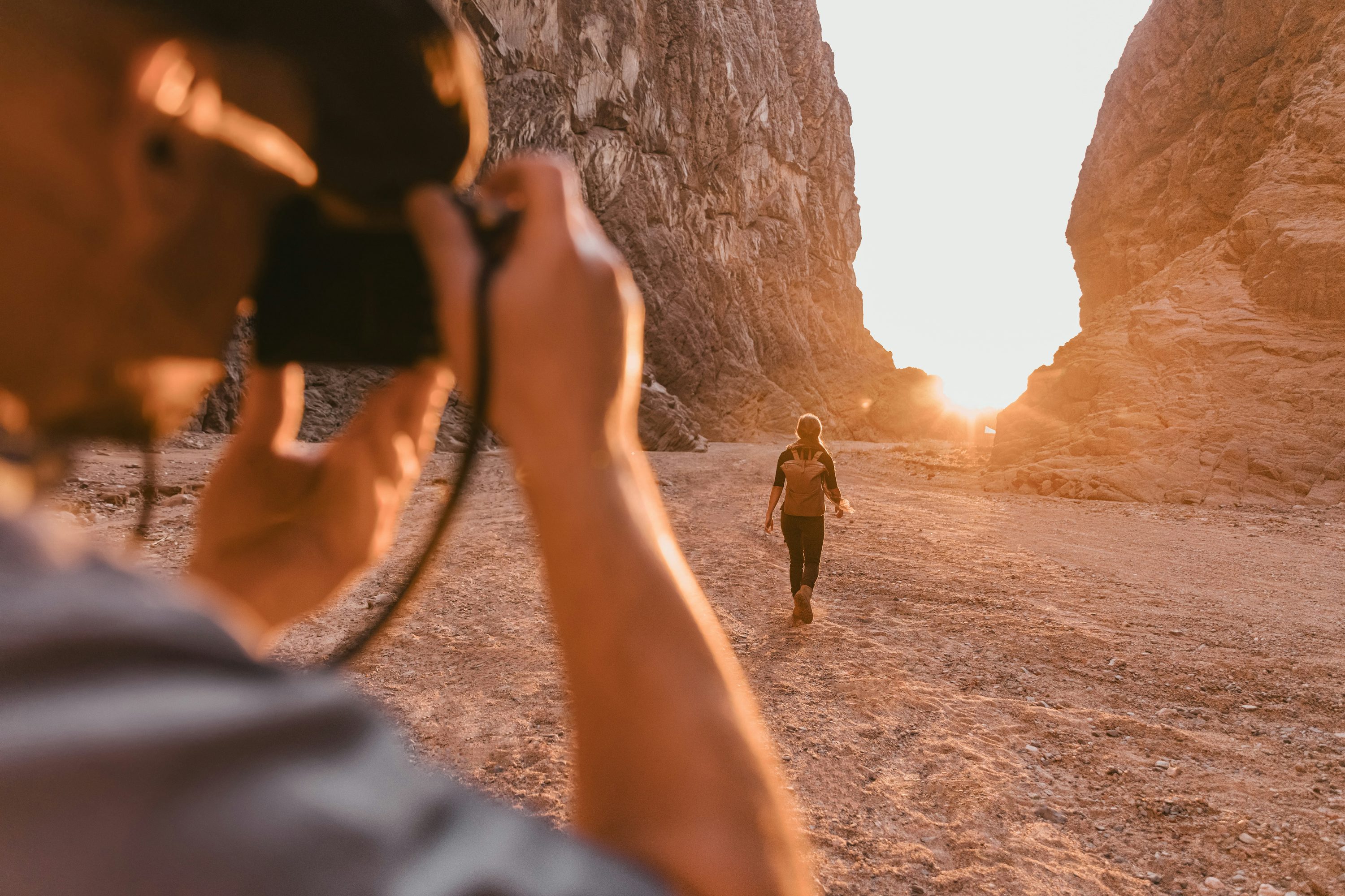 A man taking a photo of a woman walking in the desert, creating content that addresses the questions, ‘How do YouTube recommendations work?’ and ‘How does the YouTube algorithm work?’