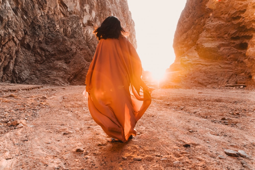 Une femme en robe orange marchant dans un canyon