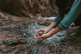 a person kneeling down and holding a rock in their hands