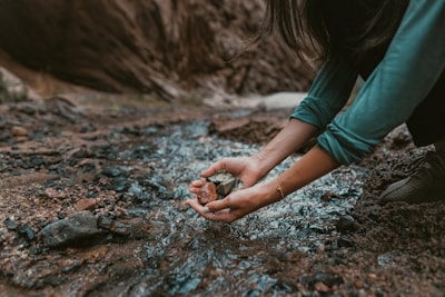 a person kneeling down and holding a rock in their hands