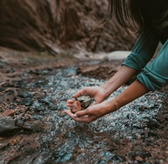 a person kneeling down and holding a rock in their hands