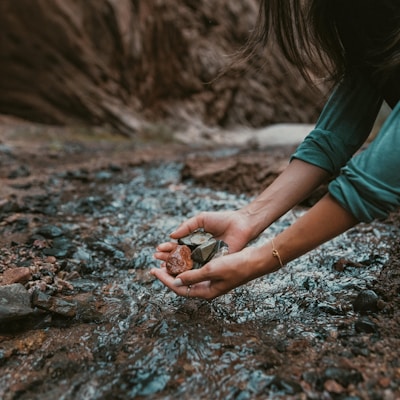 a person kneeling down and holding a rock in their hands