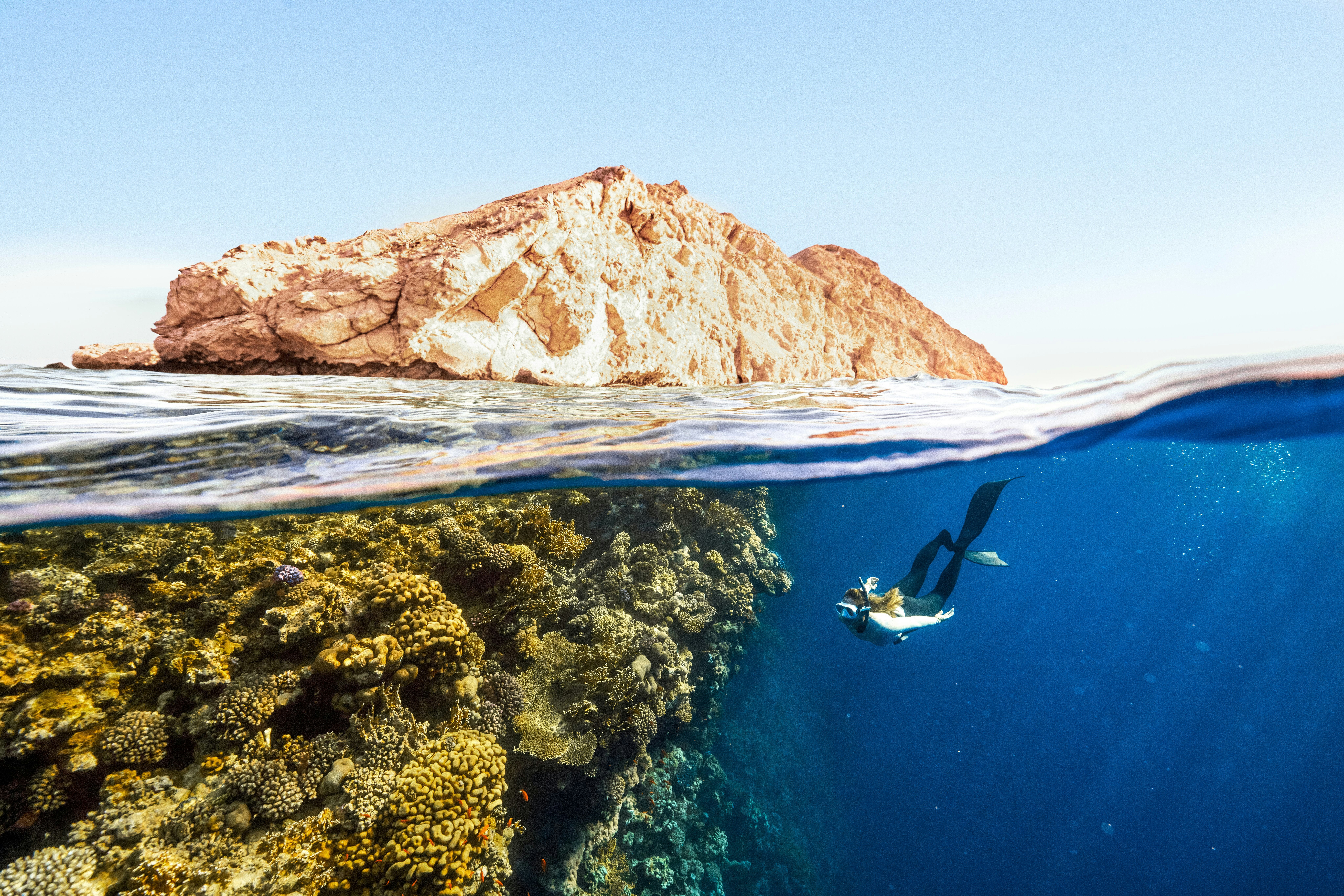 a person swimming in the ocean next to a rock