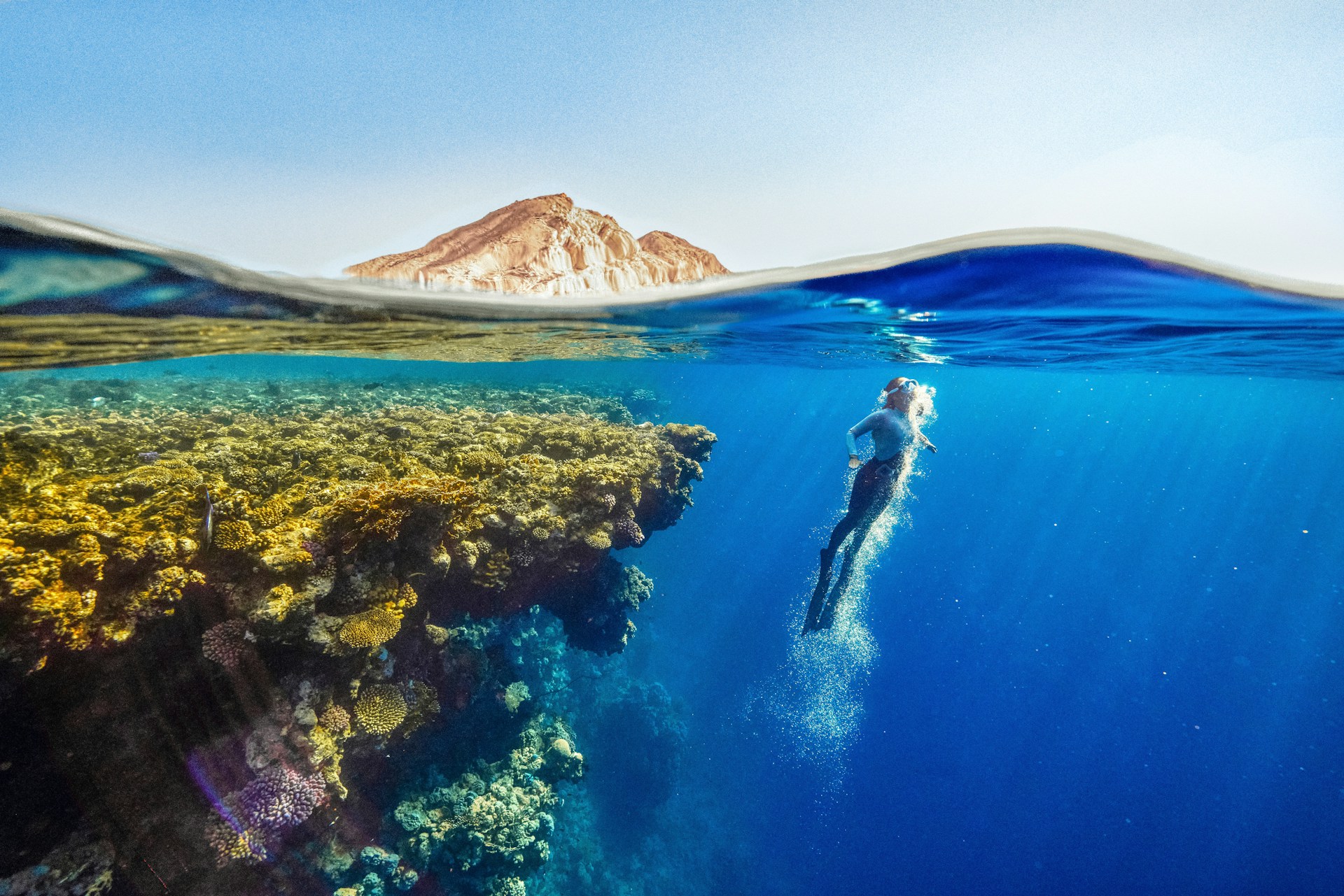 a person swimming in the ocean with a mountain in the background