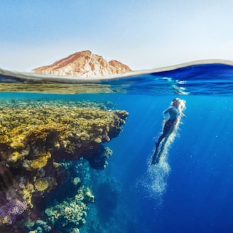 a person swimming in the ocean with a mountain in the background