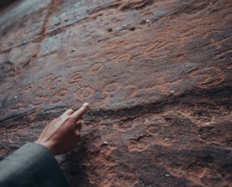 a person pointing at a rock with writing on it