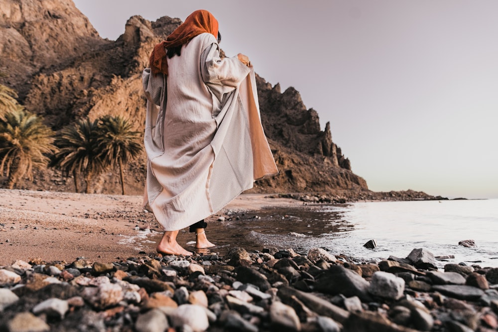 海の隣の岩だらけのビーチに立つ女性