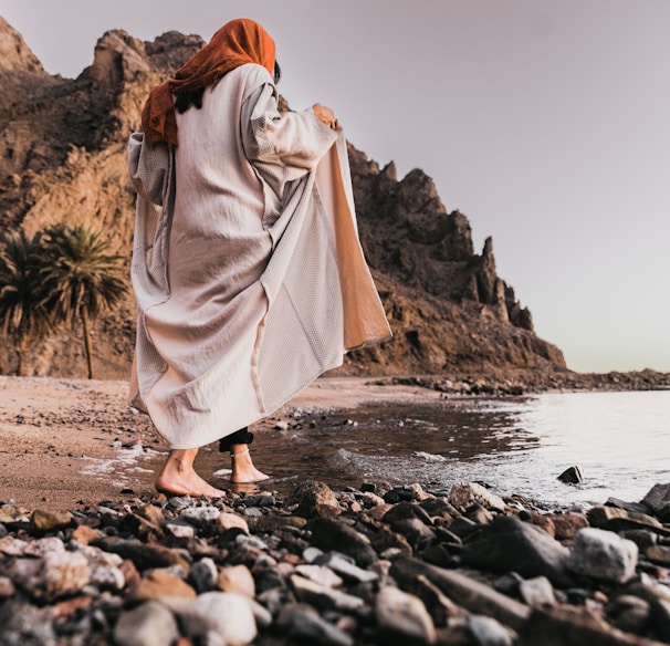 a woman standing on a rocky beach next to the ocean