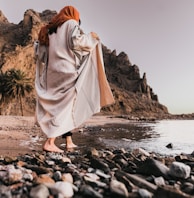 a woman standing on a rocky beach next to the ocean