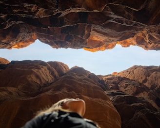 a person looking out from a cave in the desert