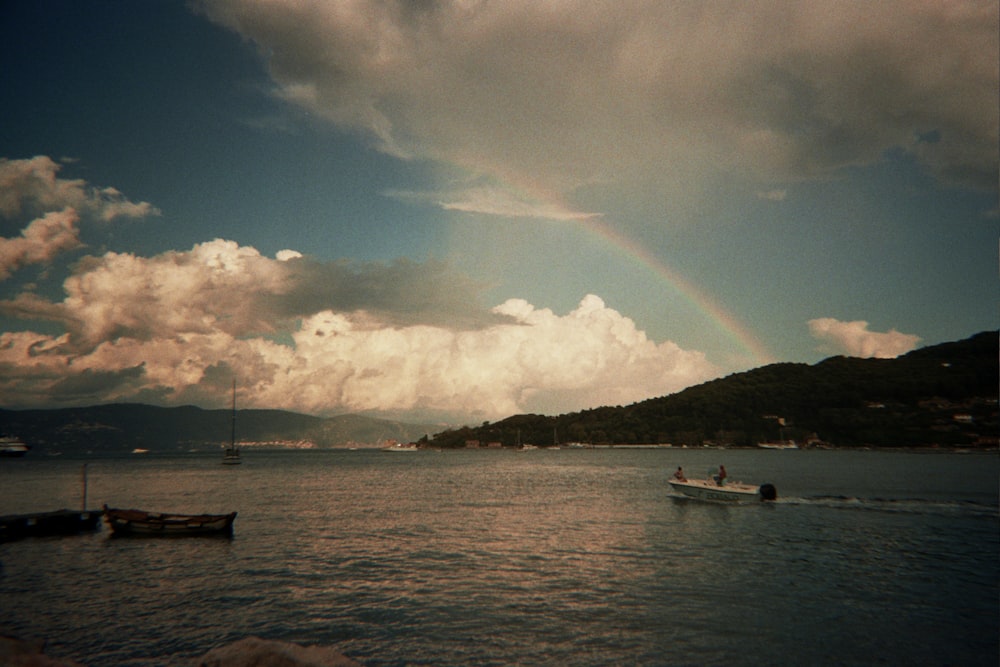 a boat in the water with a rainbow in the sky