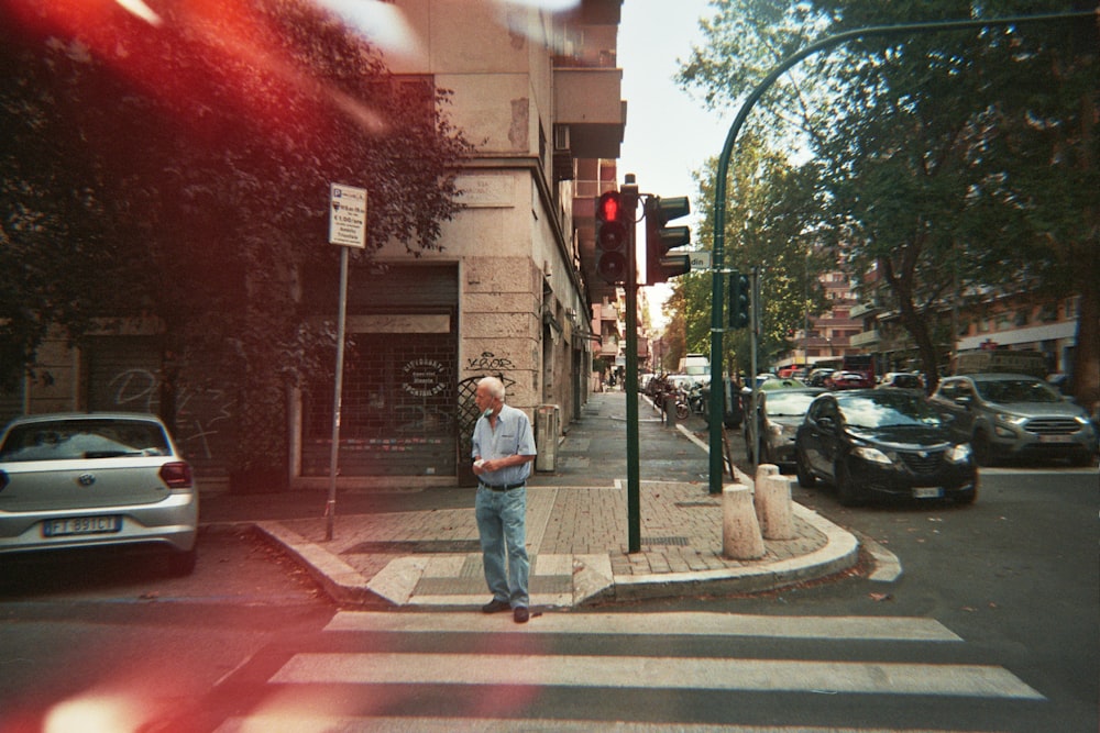 a man standing on a street corner next to a traffic light