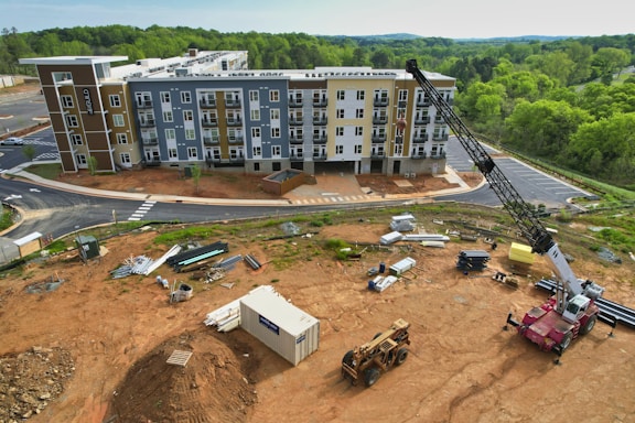 Photo of a construction site with engineers reviewing blueprints and workers building a high-end residential house.