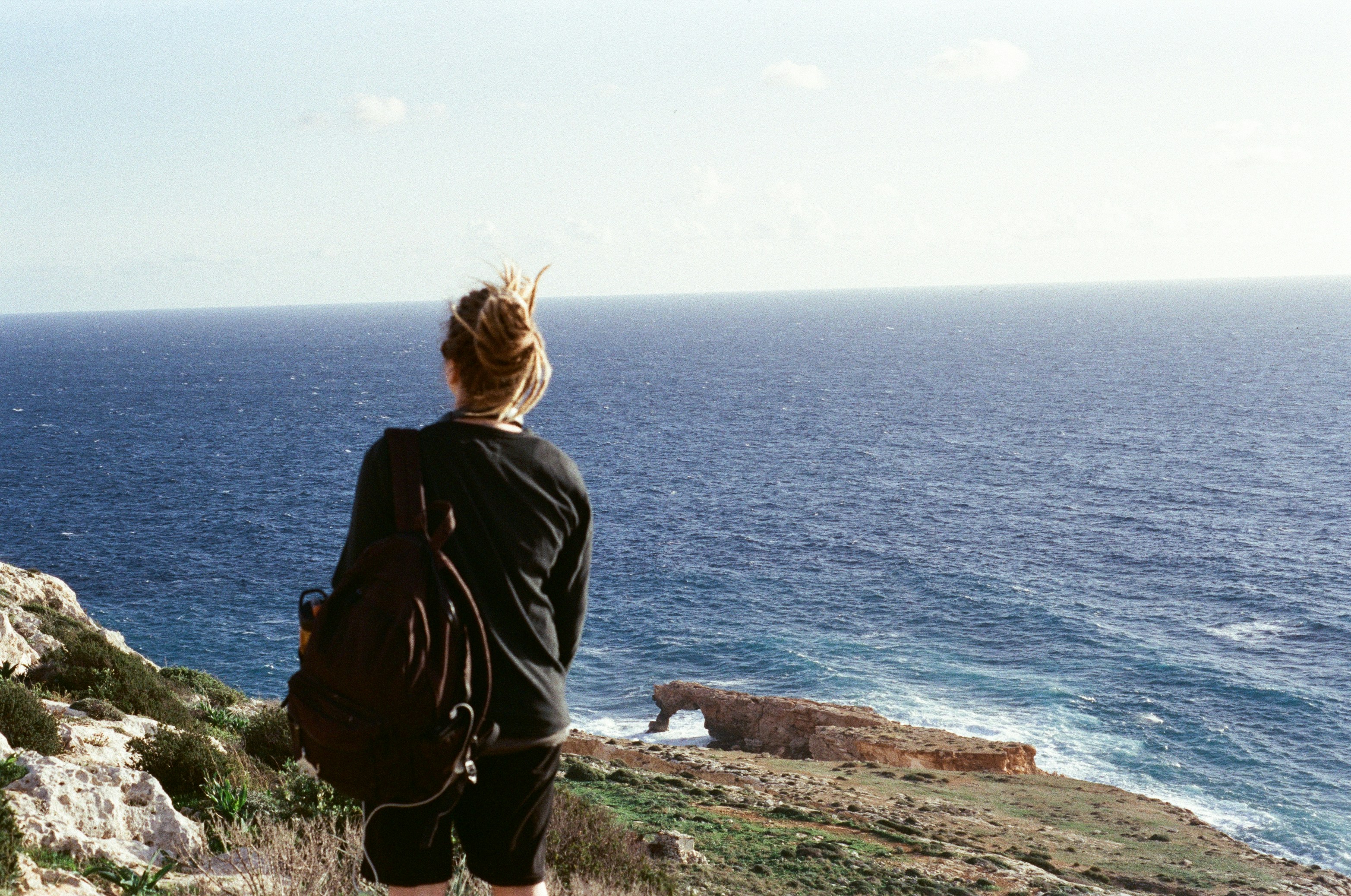 A traveler looking out at a beautiful vista, relaxed and happy - plan vacation online