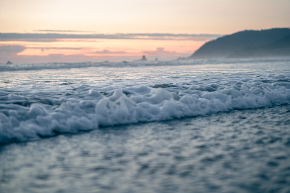 a wave rolls in on the beach as the sun sets