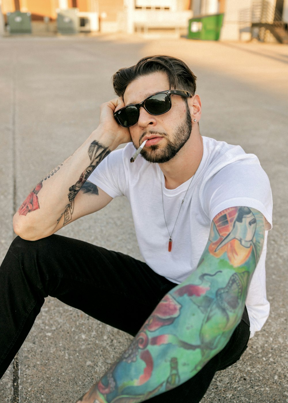 a man with tattoos sitting on the ground