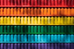 Rows of colorfully labeled decant bottles neatly aligned on a glass shelf in a boutique setting