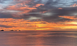 Sunset view over the Sumba sea with vibrant orange and pink hues reflecting on the water.
