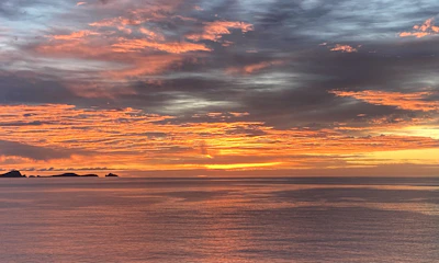 Sunset view over the Sumba sea with vibrant orange and pink hues reflecting on the water.