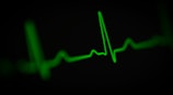 a green heart beat on a black background