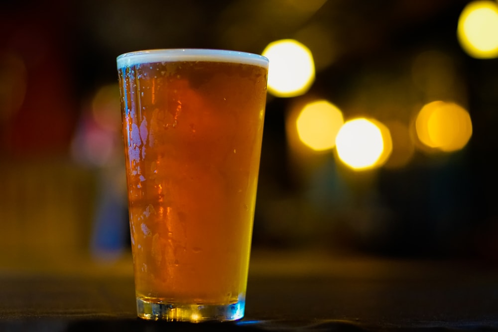 a glass of beer sitting on top of a table