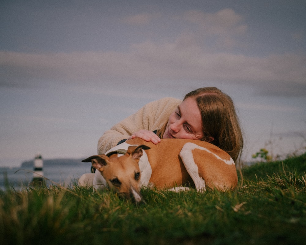 Eine Frau, die mit einem Hund im Gras liegt