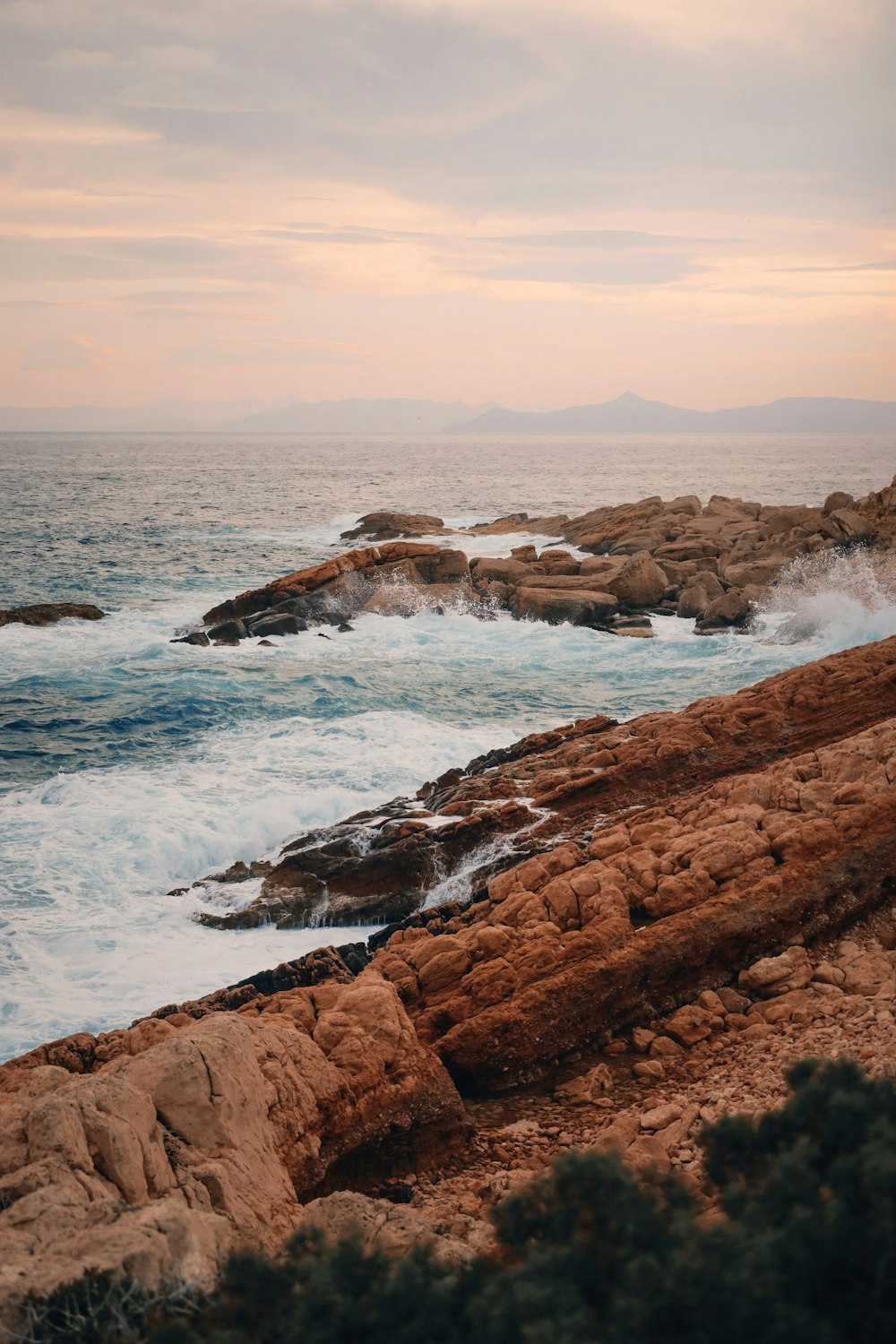 a person standing on a rocky shore next to the ocean